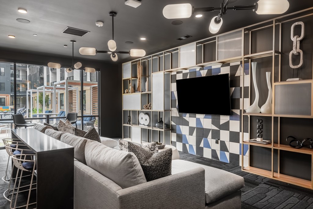 A modern living room with a grey sofa and a television mounted on the wall.