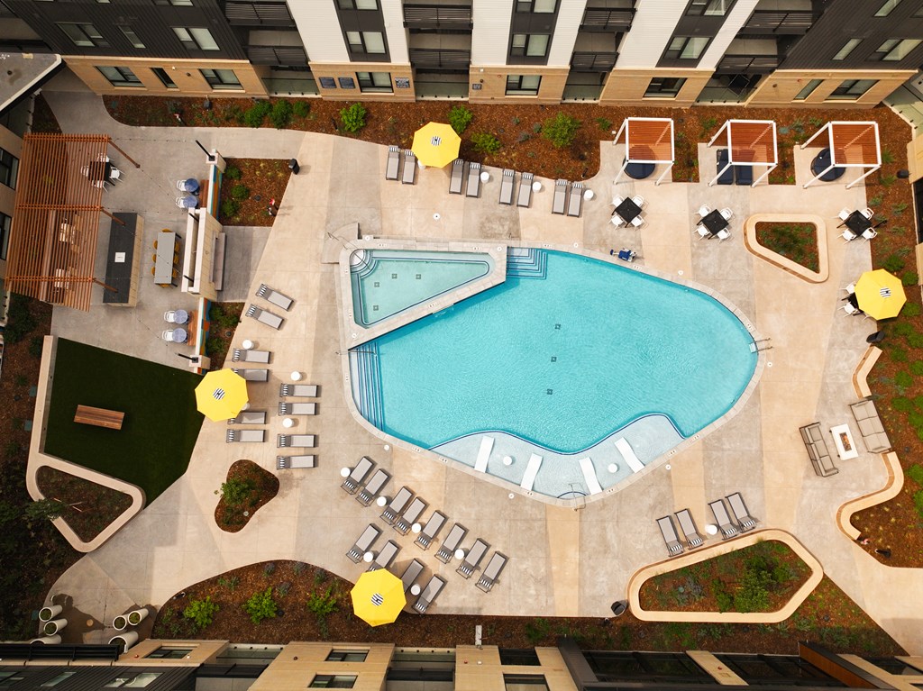 An aerial view of a pool surrounded by chairs and umbrellas.