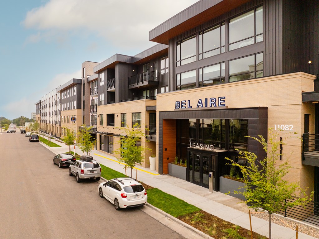 A street view of apartment buildings with cars parked on the side.