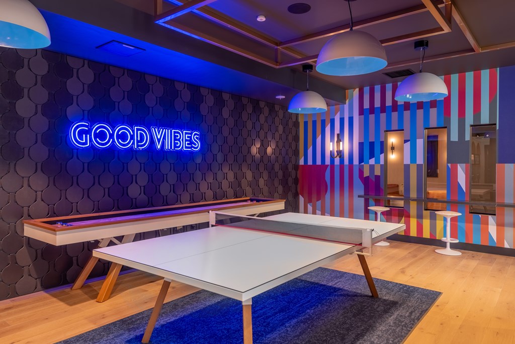 A room with a pool table and a neon sign that says "Good Vibes".