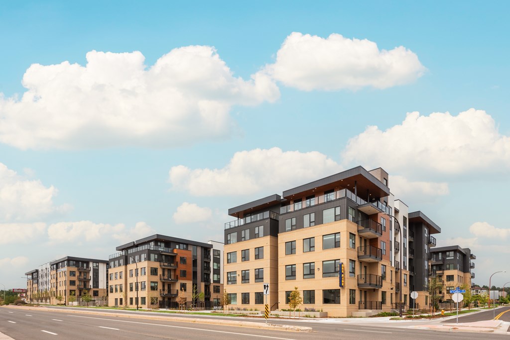 A row of modern apartment buildings are lined up on a street.