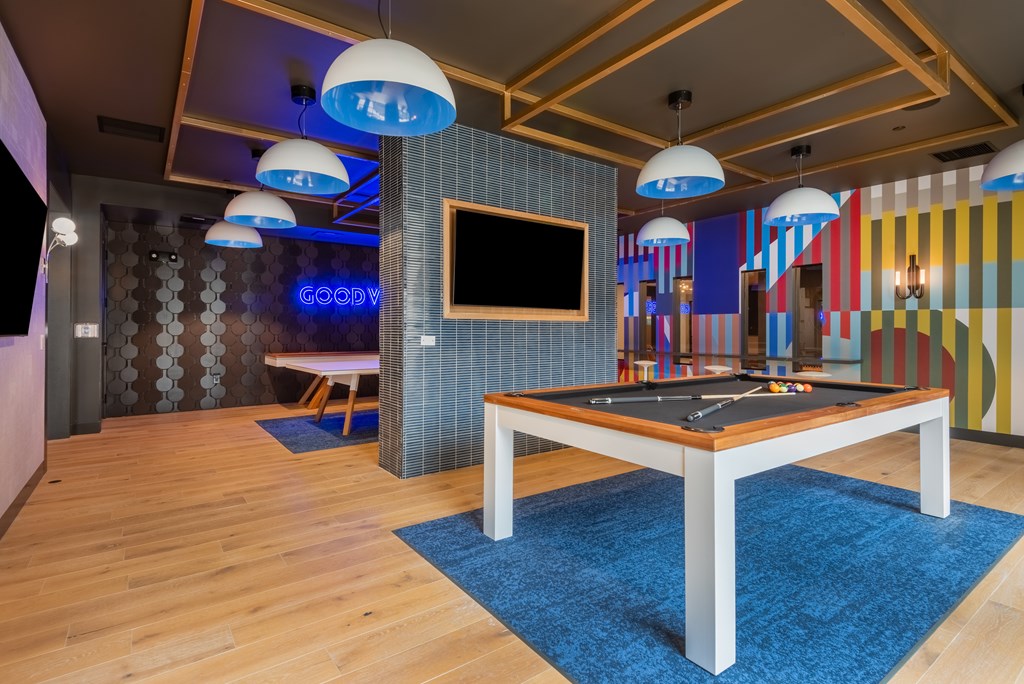 A room with a pool table and a TV mounted on the wall.