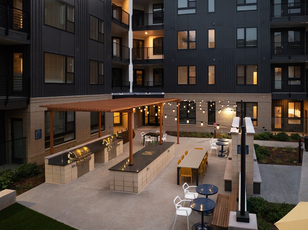 A patio area with tables and chairs is surrounded by apartment buildings.