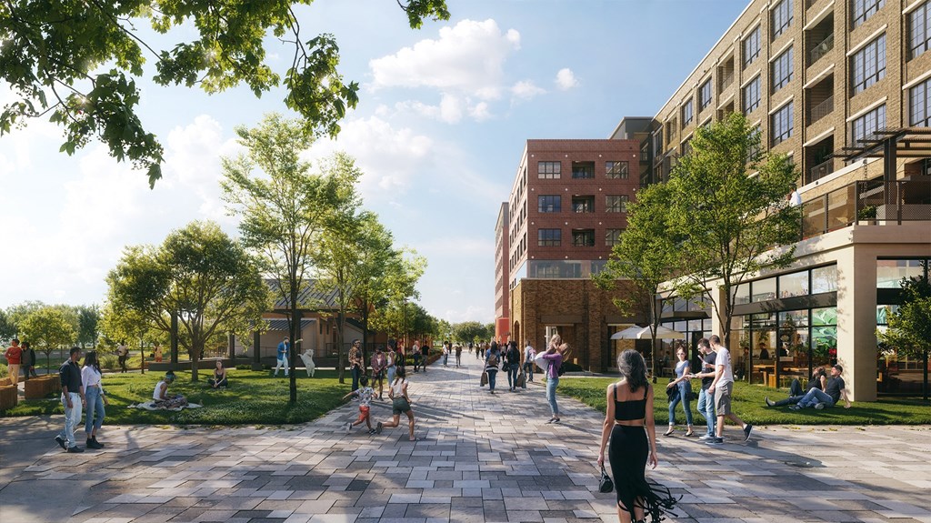 A sunny day in a park with people walking and sitting on the grass.