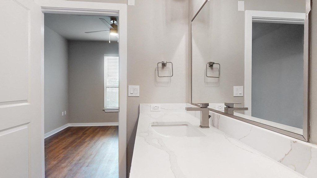Apartment bathroom with a sink and a mirror at The Can Plant Residences at Pearl, San Antonio, TX 78215and a white counter top  at The Can Plant Residences at Pearl, San Antonio, TX