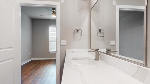 Apartment bathroom with a sink and a mirror at The Can Plant Residences at Pearl, San Antonio, TX 78215and a white counter top  at The Can Plant Residences at Pearl, San Antonio, TX