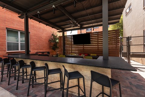 an outdoor bar with chairs in a patio at The Can Plant Residences at Pearl, San Antonio, TX, 78215