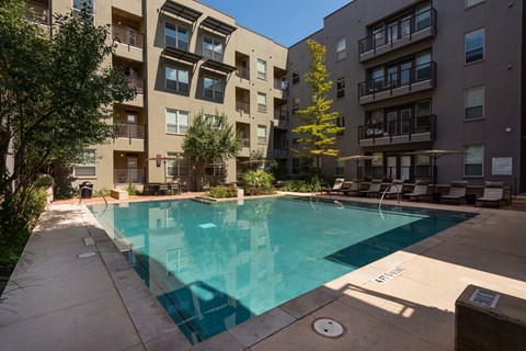 an apartment swimming pool in front of an apartment building at The Can Plant Residences at Pearl, San Antonio