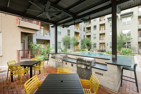 Outdoor patio with a pool and tables and chairs at The Can Plant Residences at Pearl, San Antonio, TX 78215and a white counter top