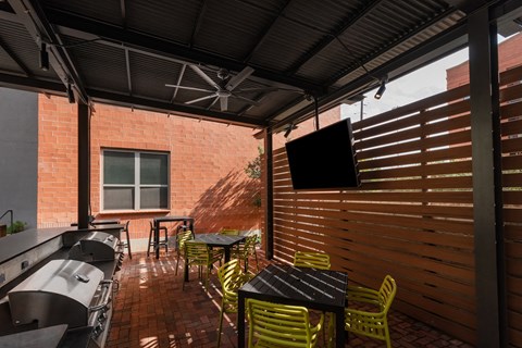 Patio with tables and chairs and a TV at The Can Plant Residences at Pearl, San Antonio, TX 78215