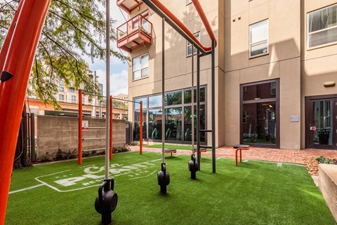 A courtyard with grass and exercise equipment at The Can Plant Residences at Pearl, San Antonio, TX 78215and a white counter top  at The Can Plant Residences at Pearl, Texas, 78215