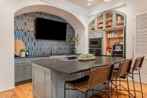 a kitchen with a large island with chairs and a tv at The Can Plant Residences at Pearl, Texas, 78215