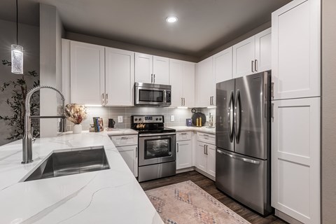 a white kitchen with stainless steel appliances and white cabinets at The Can Plant Residences at Pearl, San Antonio