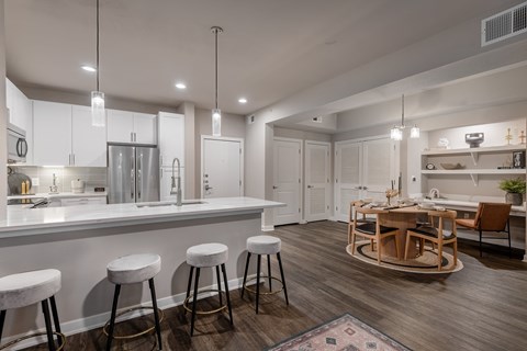 an open kitchen and living room with a bar and stools at The Can Plant Residences at Pearl, San Antonio, 78215