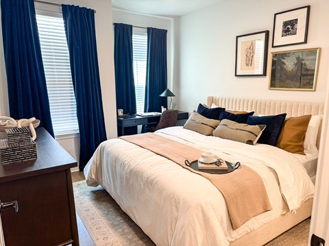A bedroom with a large bed and a window with blue curtains.