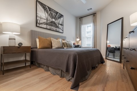 A bedroom with a bed, nightstand, and a painting on the wall.