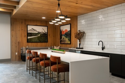 A kitchen with a white counter and brown chairs.