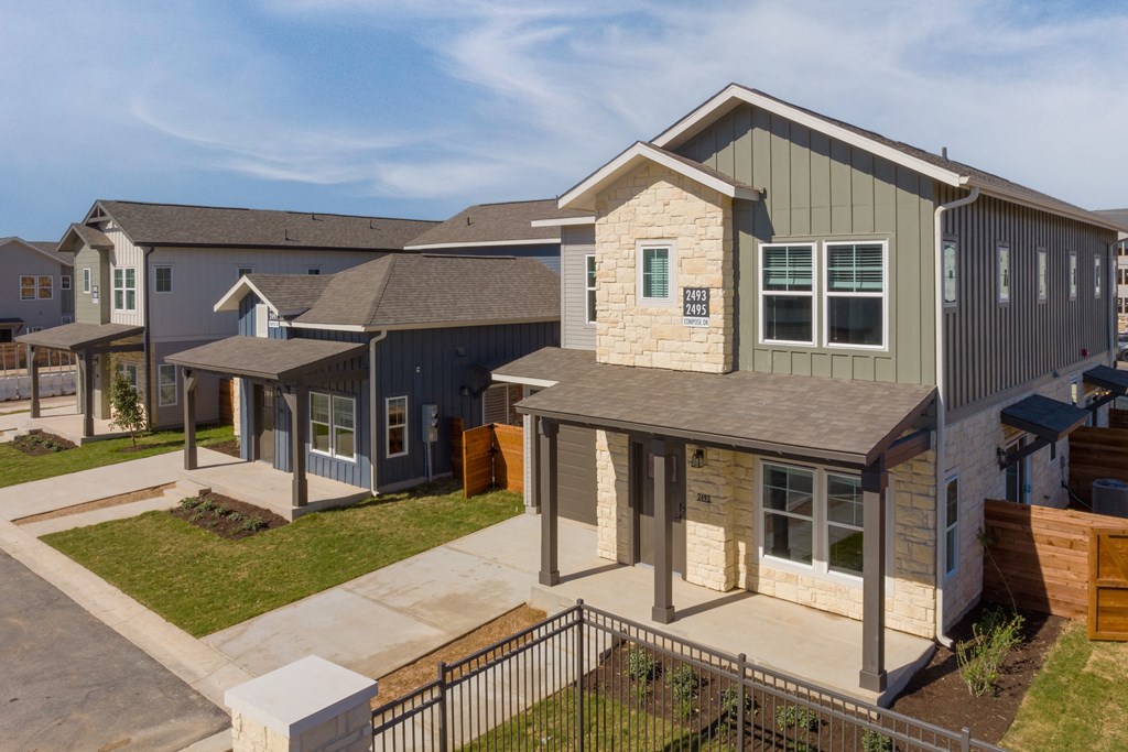 a group of homes in a row with a sidewalk and grass