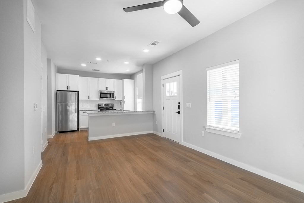 an empty living room and kitchen with white walls and wood floors