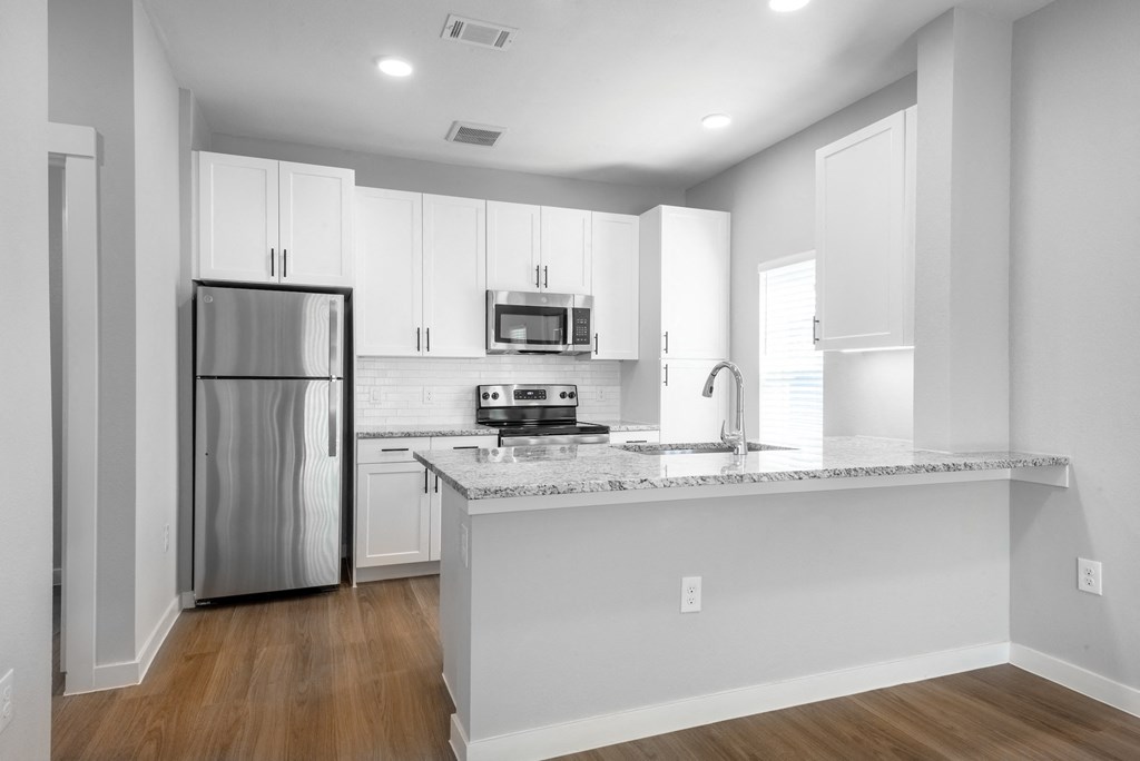 an empty kitchen with an island and stainless steel refrigerator