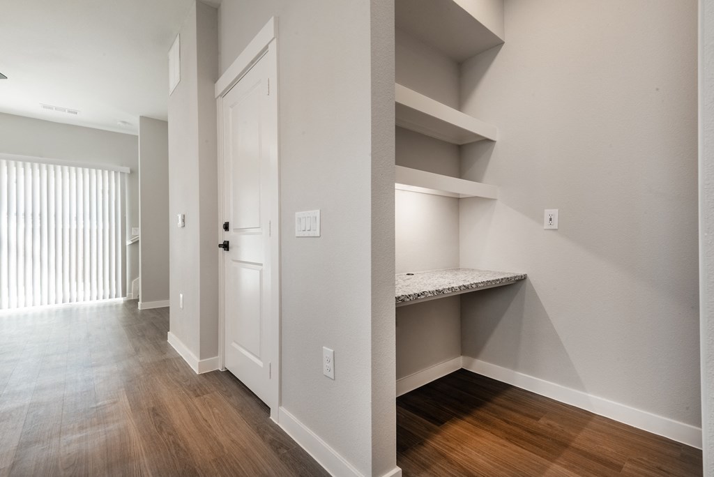a bedroom with a closet and a door to a hallway with a desk and shelves