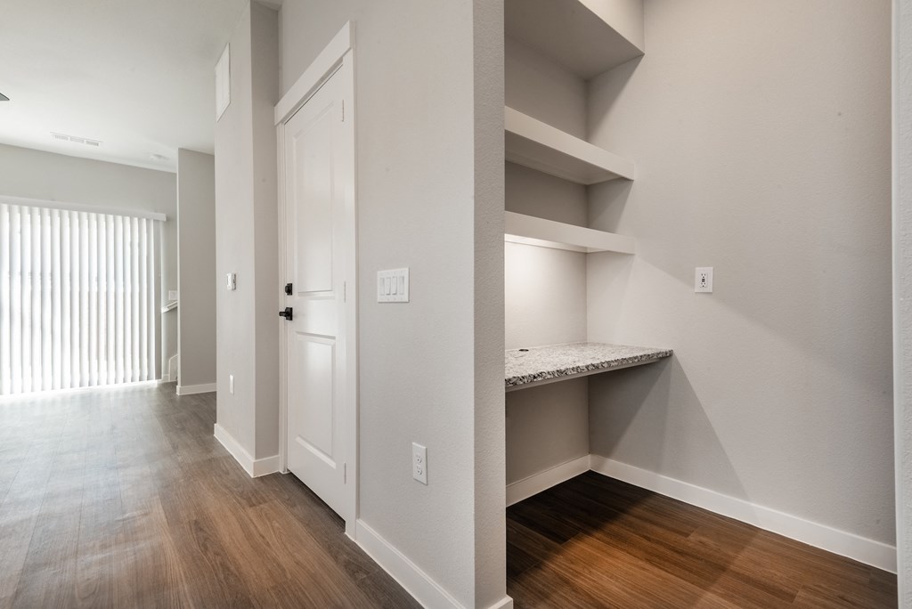 a bedroom with a closet and a door to a hallway with a desk and shelves