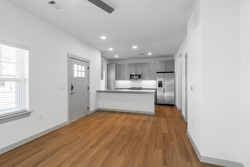 a living room and kitchen with white walls and wood floors