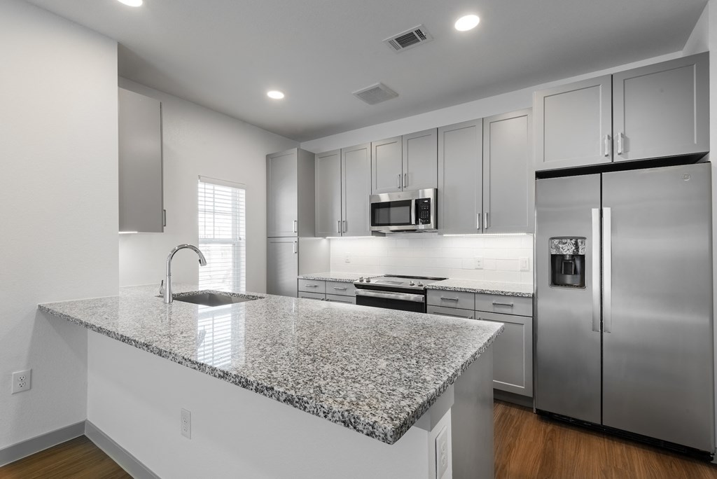 a kitchen with a granite counter top and stainless steel refrigerator