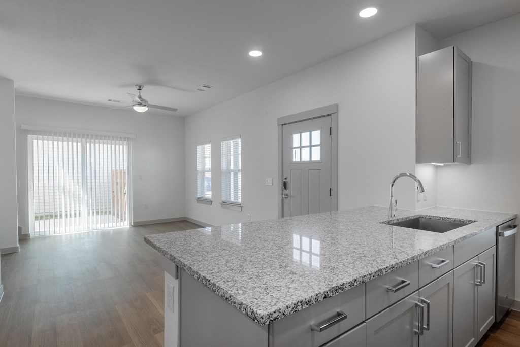 an open kitchen and living room with a marble counter top