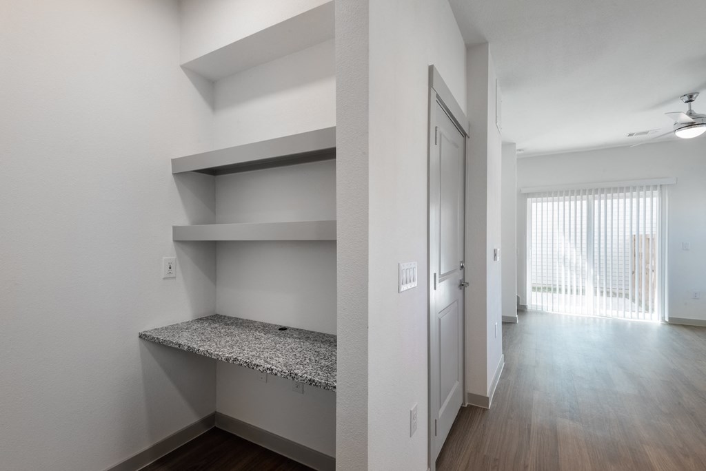 the living room and hallway of an apartment with white walls and wood flooring