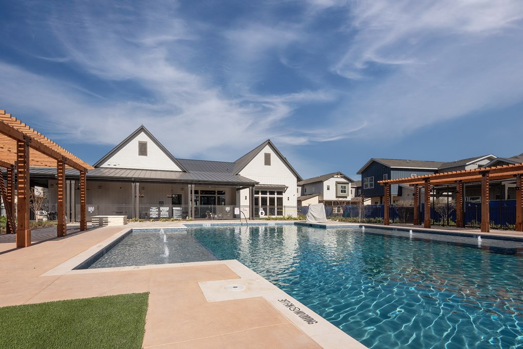 a large swimming pool with a house in the background