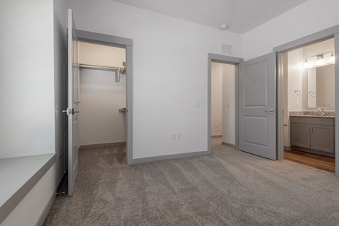 a bedroom with two closets and a bathroom with a sink and a mirror