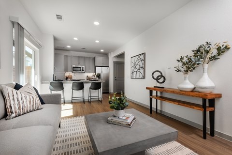 a living room with a couch and a coffee table in front of a kitchen