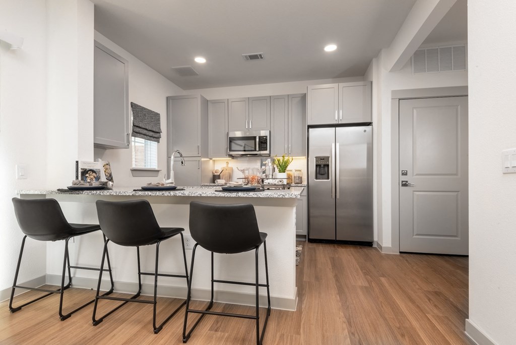 a kitchen with a large island with three chairs
