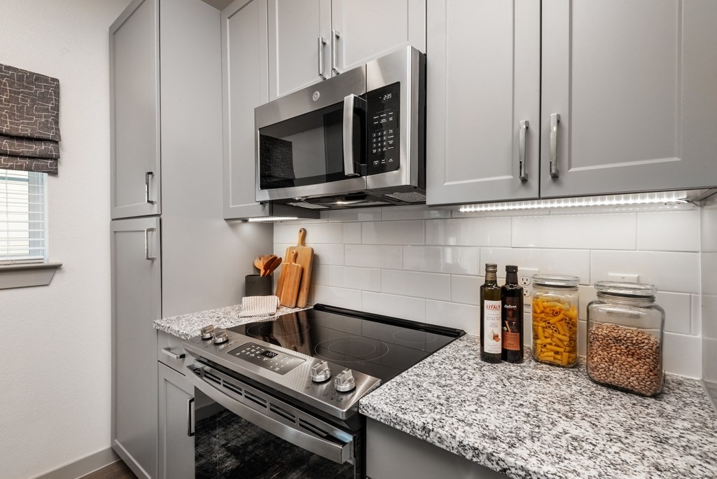 a kitchen with white cabinets and a stove and a microwave