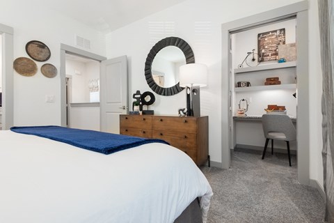 a bedroom with a bed and a desk and a mirror