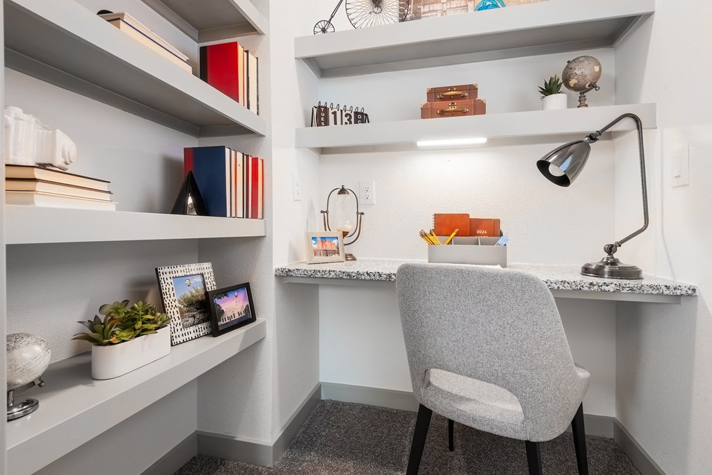 a desk with a chair and shelves in a small room
