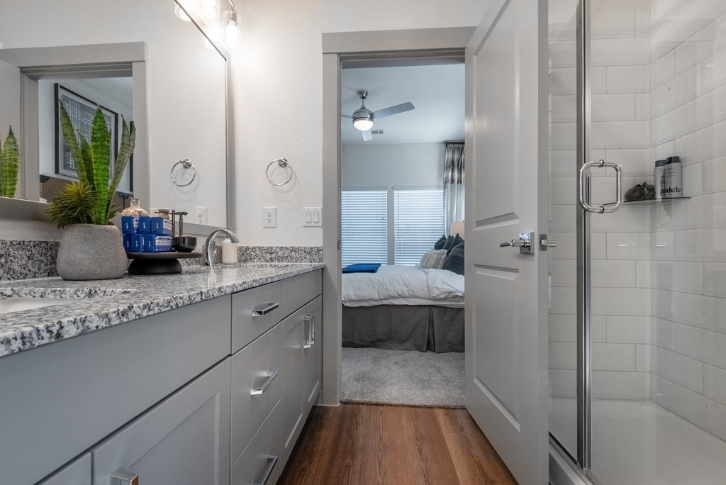an open bathroom with a shower and a bedroom in the background