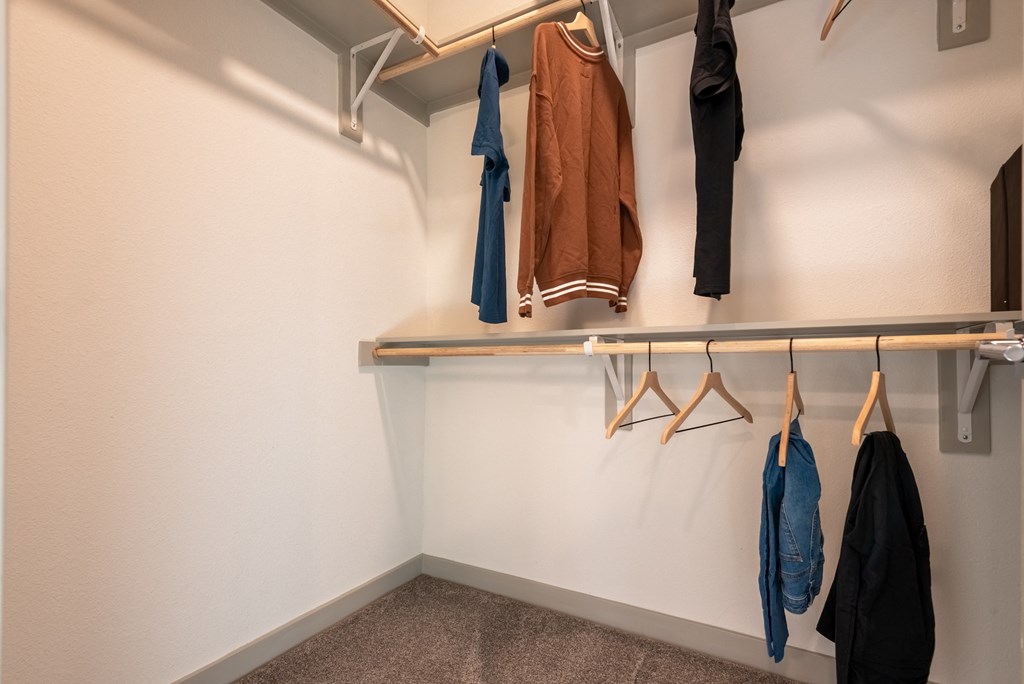 a well lit closet with coats hanging on a rack