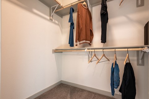 a well lit closet with coats hanging on a rack
