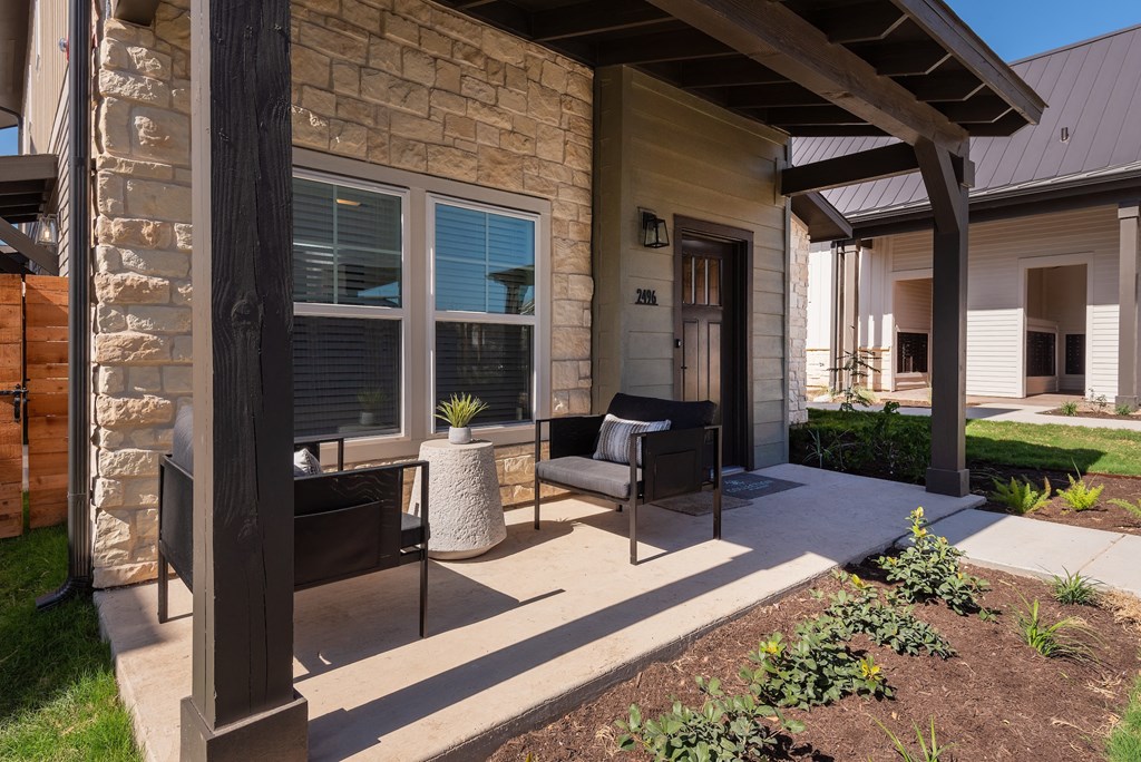 a patio with two chairs and a table in front of a house