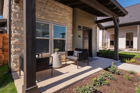 a patio with two chairs and a table in front of a house