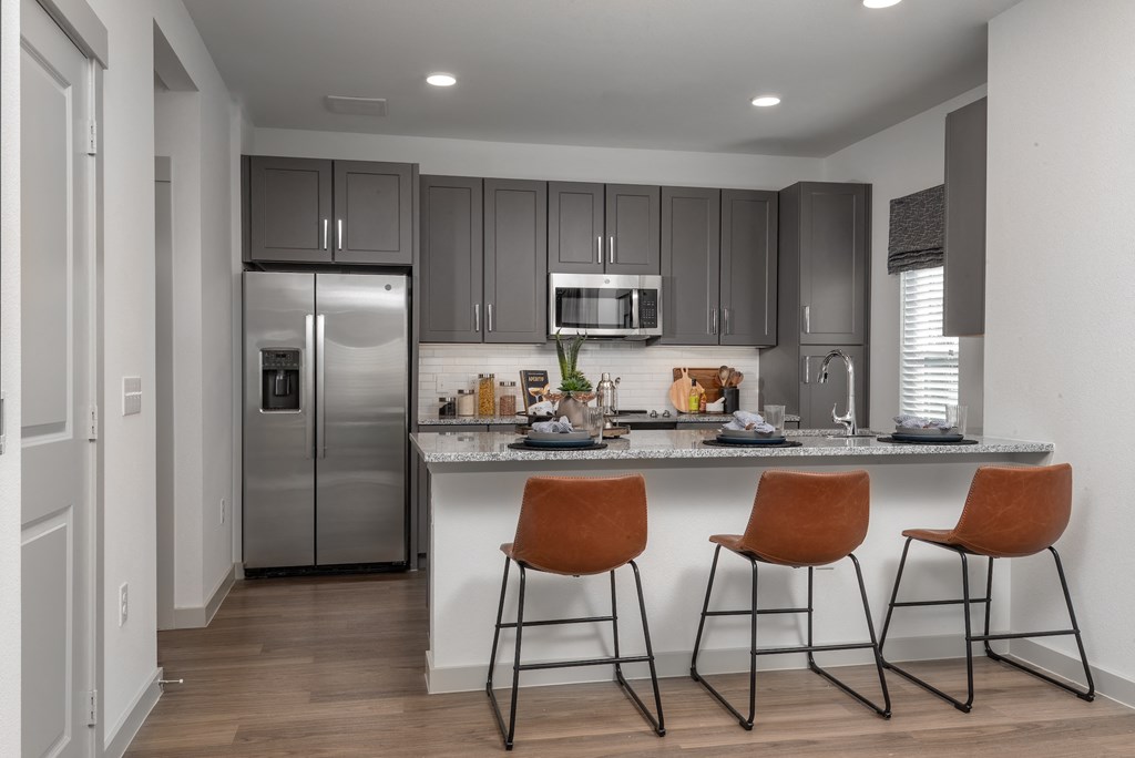 a kitchen with stainless steel appliances and a counter with three stools