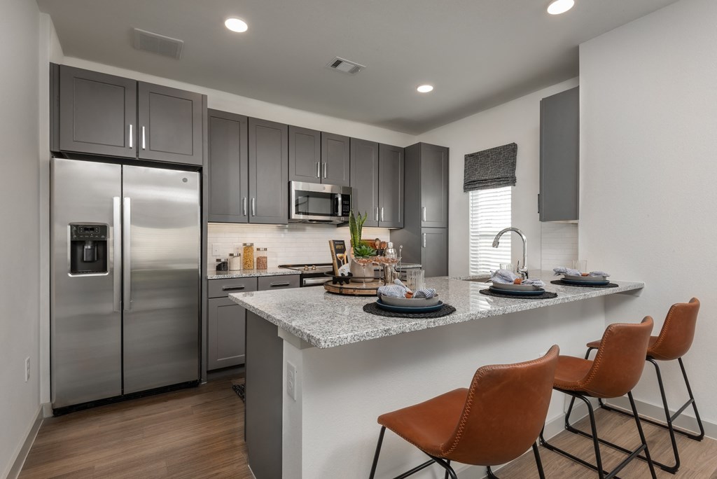 a kitchen with stainless steel appliances and a counter with chairs