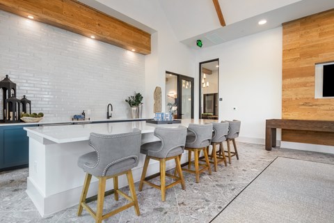 a kitchen with a long counter and bar chairs