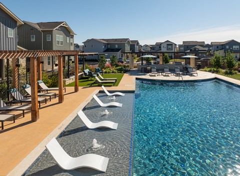 A pool with a wooden deck and white chairs.
