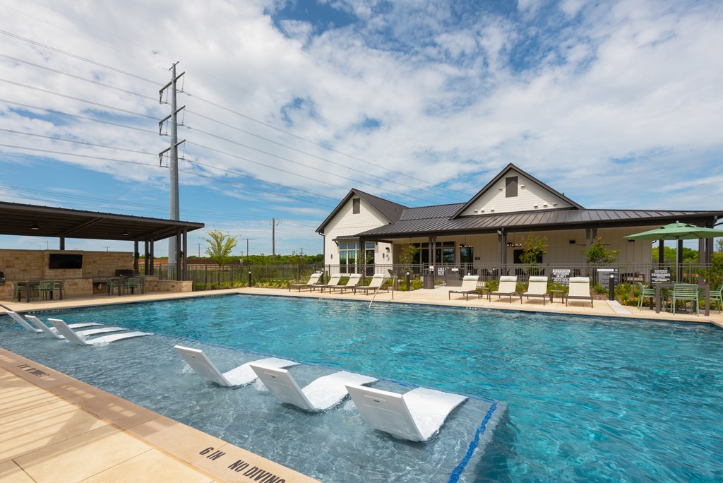 A pool with a blue line in the middle and white chairs around it.