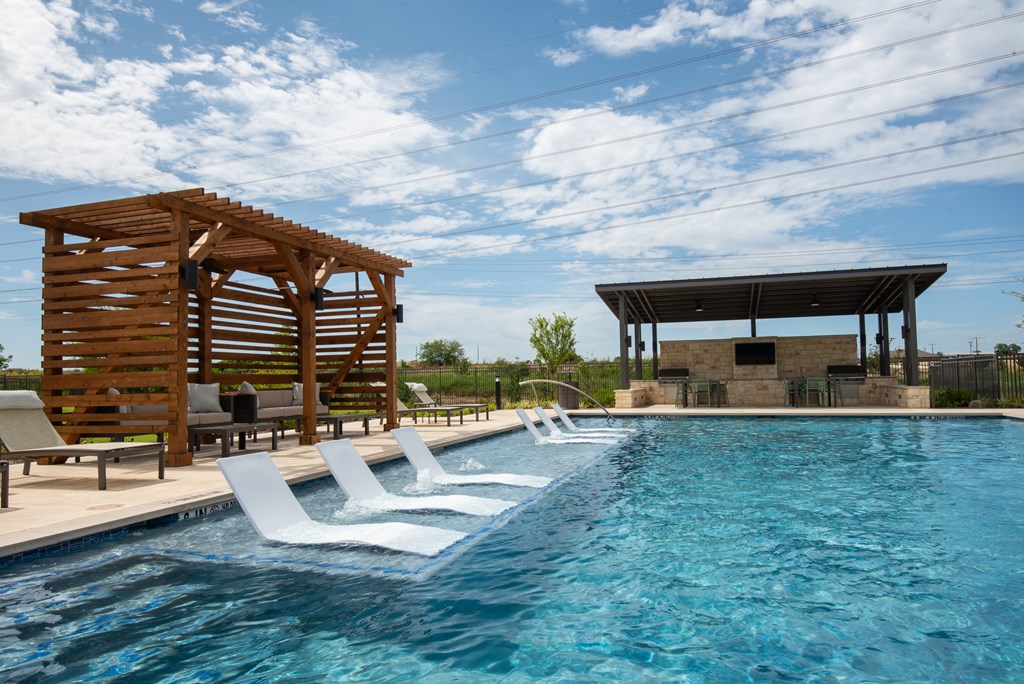 A pool with a wooden structure and lounge chairs.