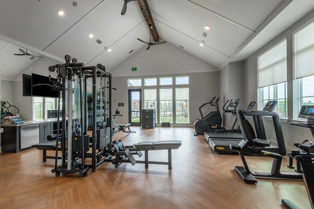 A spacious gym with a variety of equipment including treadmills, weight machines, and a bench press.