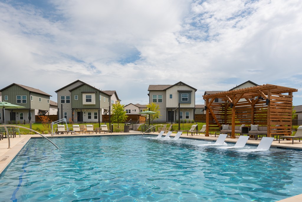 A swimming pool in front of a row of houses.